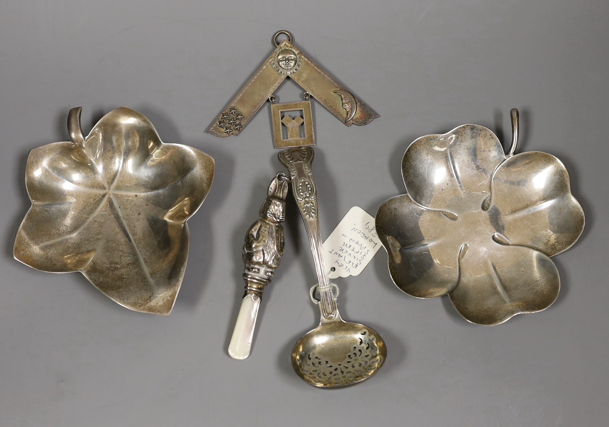 Two Tiffany & Co sterling leaf dishes, largest 14.6cm and three other items including a child's silver rattle, silver masonic jewel and a late Victorian silver sifter spoon.